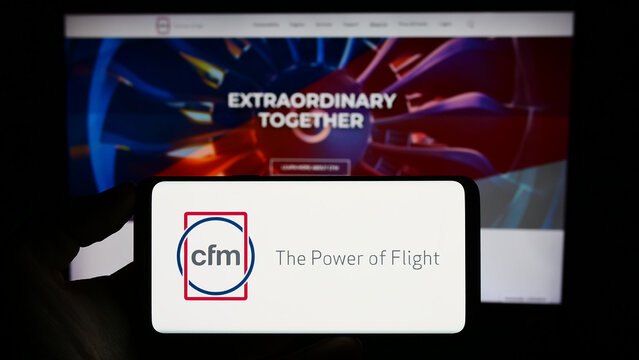 Stuttgart, Germany - 09-22-2023: Person holding smartphone with logo of aircraft engine company CFM International on screen in front of website. Focus on phone display.