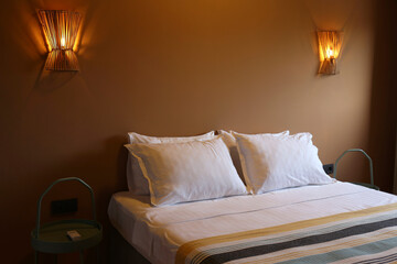 Stylish bedroom with an empty king sized bed and sconce light fixtures glowing in the evening....