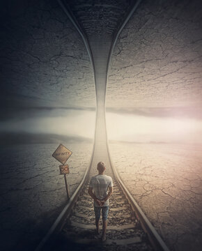 Infinity road concept with a man walking the railway to the parallel world above. Surreal and mysterious scene, adventure journey on the endless way