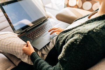 A woman uses a laptop touchpad while sitting at home