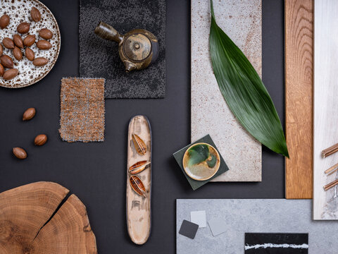Creative flat lay composition in grey and navy color palette with textile and paint samples, lamella panels, leaves and tiles. Architect and interior designer moodboard. Top view. Copy space.