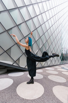 Dancer with dyed hair dancing in front of building
