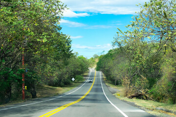 Automóvil el la carretera en la mitad del campo tropical