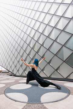 Young dancer dancing in front of modern patterned wall