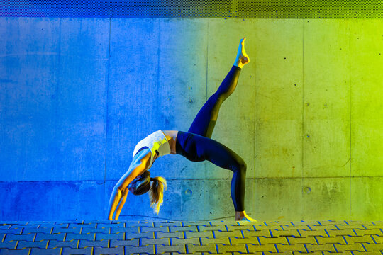 Woman exercising in front of neon colored wall