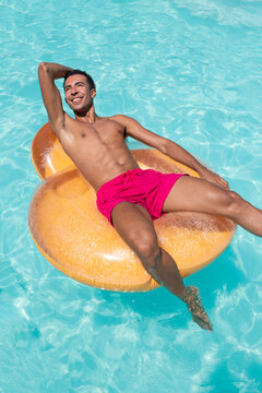 Happy young man sitting on inflatable float in pool