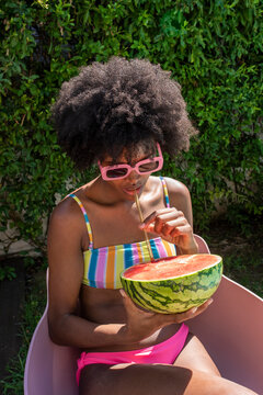 Young woman drinking watermelon juice with straw on sunny day
