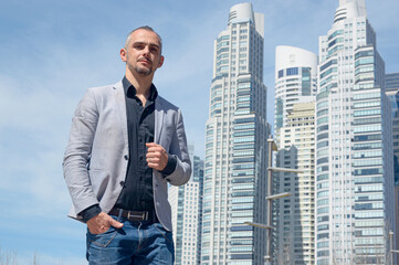 Fototapeta premium caucasian business man standing outdoors looking at camera holding blazer with one hand
