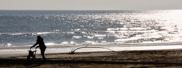 Fototapeta na wymiar Sagoma di persona che cammina in spiaggia vicino al mare