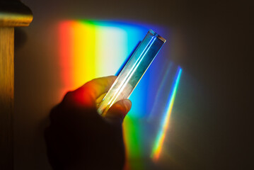 hand holding a prism rainbow effect on a wall colorful light science 