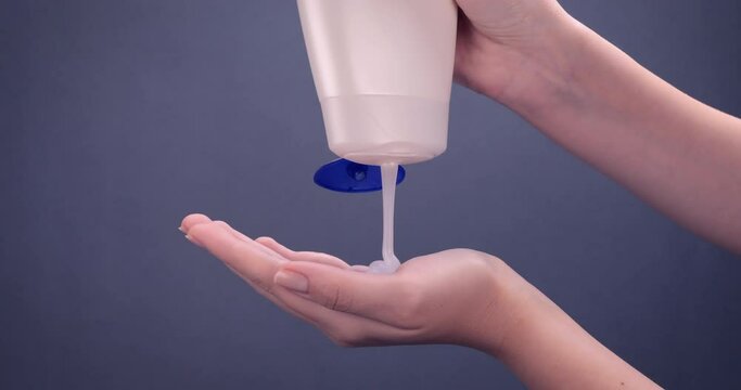 Shower gel in white bottle poured into woman palm. Concept of skin feeling fresh, clean and revitalized with the body wash. Skincare, wellness, hygiene concept. Slow motion 4k