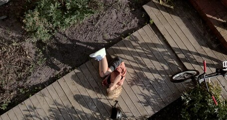 OVERHEAD slow motion shot of a kid falling from a bicycle while doing trick