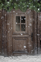 Tür in einer verschneiten Berghütte mit Tannenzweigen