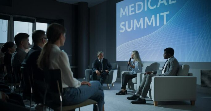 International Medical Summit: Host Asking Caucasian Female Pharmaceutical CEO a Question In Front Of Audience Of Diverse Attendees. Woman Talking About New Developments In Biotechnology, Medicine.