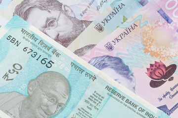 fifty Indian rupee banknote lying on Ukrainian hrivnya banknotes