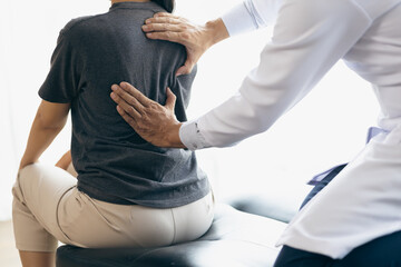 Doctor examining woman back pain in examination room. Doctor practicing back and shoulder...