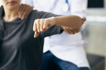 Doctor practicing arm and shoulder physiotherapy for female patient in hospital.