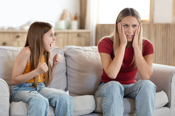 Tired mom touching head, feeling desperate about screaming daughter teenager