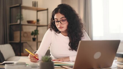 Boring tired young student freelancer with glasses can not study or work making notes at home workplace Stressed curly female exhausted from remote distance work or education and hard program indoors