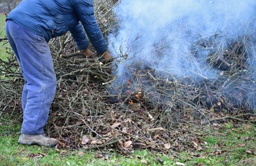 
A gardener burns waste branches in a garden in a village traditionally
