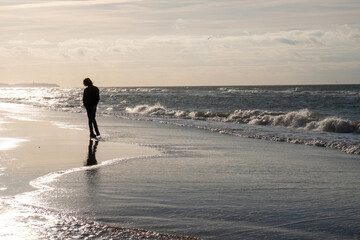 A lone wanderer embarks on a poignant journey along the serene shores of Cap-Blanc-Nez, France....