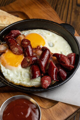 delicious breakfast with egg and sausages in a frying pan on a wooden table