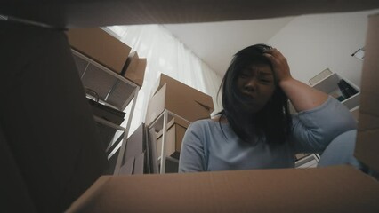 Asian woman unpacking parcel box, upset with broken items, bad shipping service
