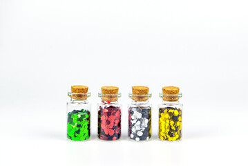 Colorful sparkles in glass bottles isolated on white background.