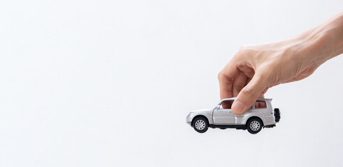 Hand holding a toy car isolated on gradient background. After some edits.