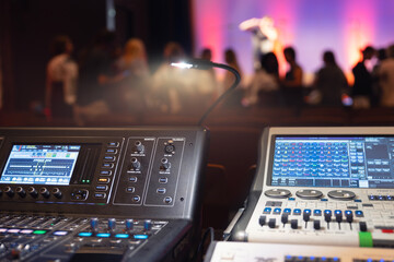 Live theater concert show sound video music control console with scene lights background. Sound engineer mixer soundboard equipment with many knobs, buttons, faders, equalizer screen and light - obrazy, fototapety, plakaty