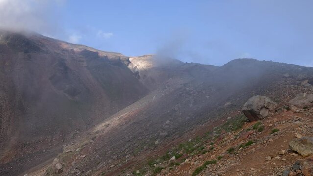 Fast moving fog and mist on rocky terrain near summit of Asahidake