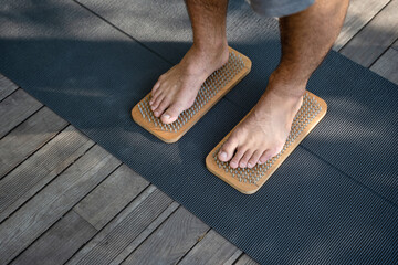 Standing on nails. Male bare feet near needle boards. Yoga practice.