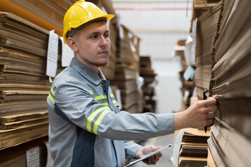 Male warehouse worker working and inspecting quality of cardboard in corrugated carton boxes warehouse storage. Male worker checking quality of barcodes on cardboard - obrazy, fototapety, plakaty