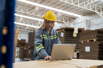 Female warehouse worker working and inspecting quality of cardboard in corrugated carton boxes warehouse storage. Female worker checking quality of barcodes on cardboard