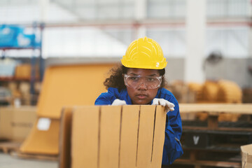 Female warehouse worker working and inspecting quality of cardboard in corrugated carton boxes warehouse storage. African American female worker checking cardboard from cardboard making machine - obrazy, fototapety, plakaty