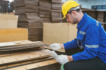 Male warehouse worker working and inspecting quality of cardboard in corrugated carton boxes warehouse storage