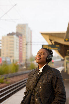 Young woman listening to music while waiting for train