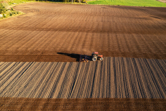 Aerial view of tractor plowing field at sunset