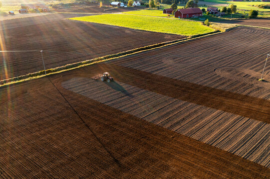Aerial view of tractor plowing field at sunset
