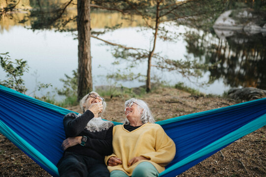 Two senior women resting in hammock at lakeshore