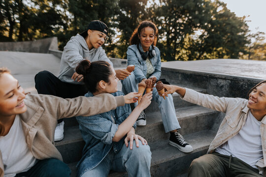 Teenagers sitting in skate park and give each other fist bump - Powered by Adobe