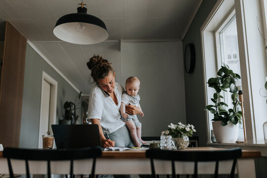 Multitasking mother taking care of baby and working from home