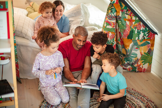 Young blended family reading together in the bedroom at home