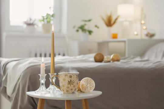 cup of coffee with christmas balls on little table in white bedroom
