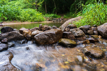 A small waterfall with many rocks in the stream. Surrounded by trees in the mountain forest.