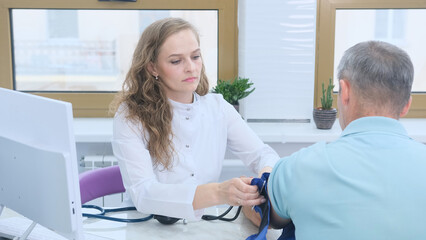 Fototapeta premium A doctor measuring the blood pressure of an elderly patient.