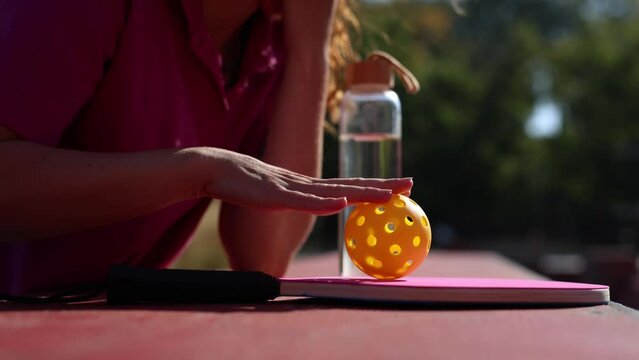 Female athlete rolling a ball for pickleball on a racket in close up