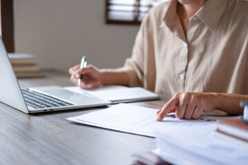 Businesswoman working on laptop and papers.