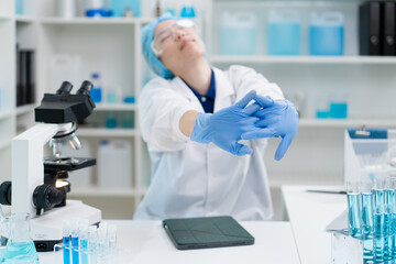 hand of scientist stretching rest from tired working overtime in laboratory, asian female doctor...