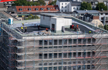 Birdseye view of roofer waterproofing the flat roof of a commercial building.